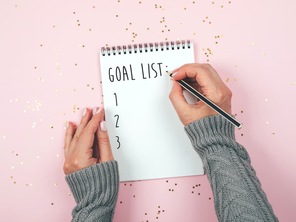 person setting out their goals on their notepad